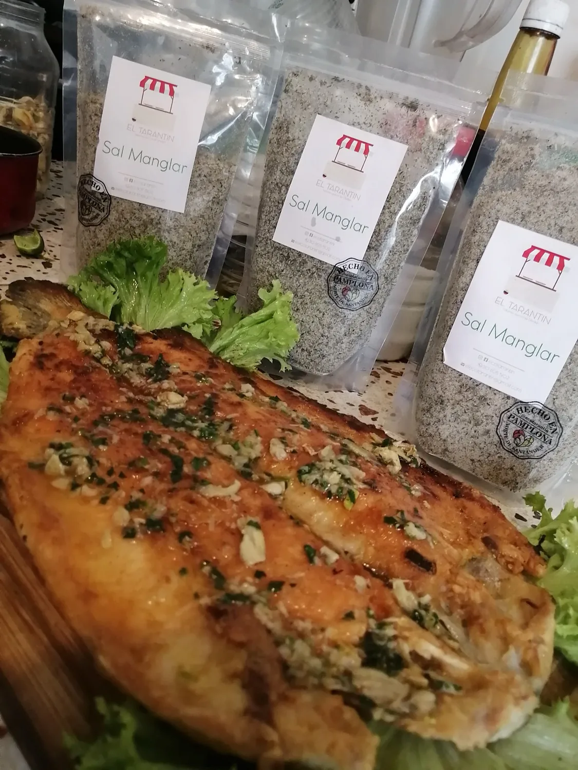Sazonadores naturales El Tarantin sin conservantes junto a un pescado asado a la parrilla