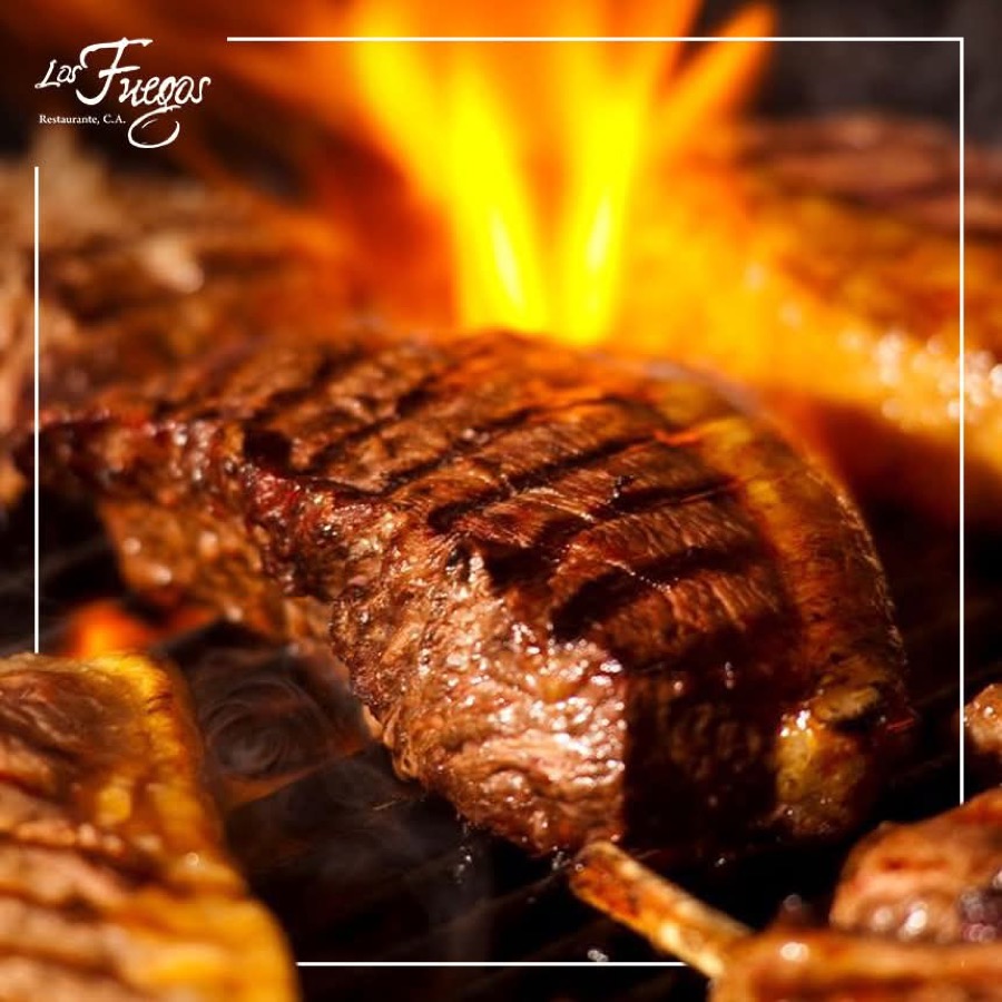 Carne en vara asándose junto al fuego en Los Fuegos
